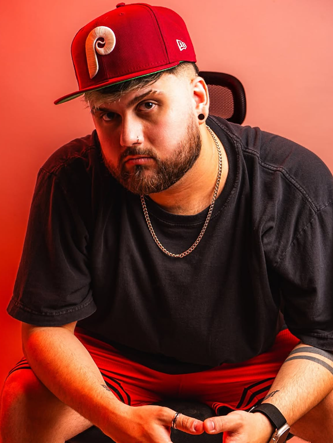 Juampa sentado, con gorra roja y remera negra, mirando a cámara
